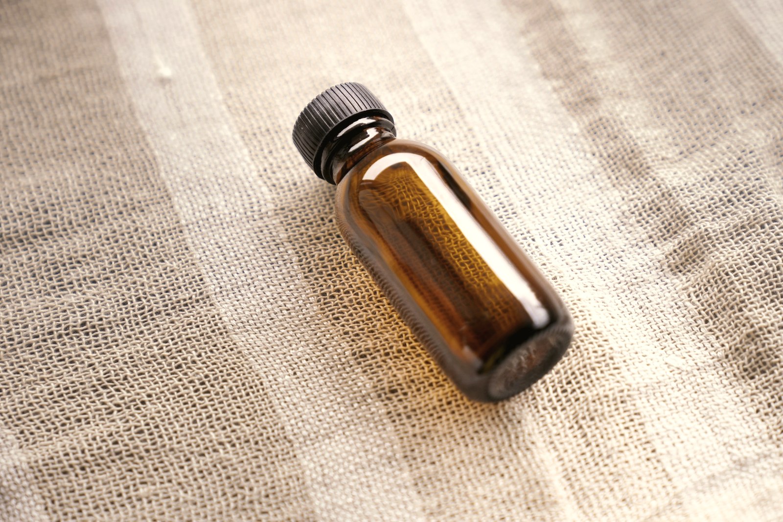 An amber glass serum bottle on natural linen, the packaging retinaldehyde requires