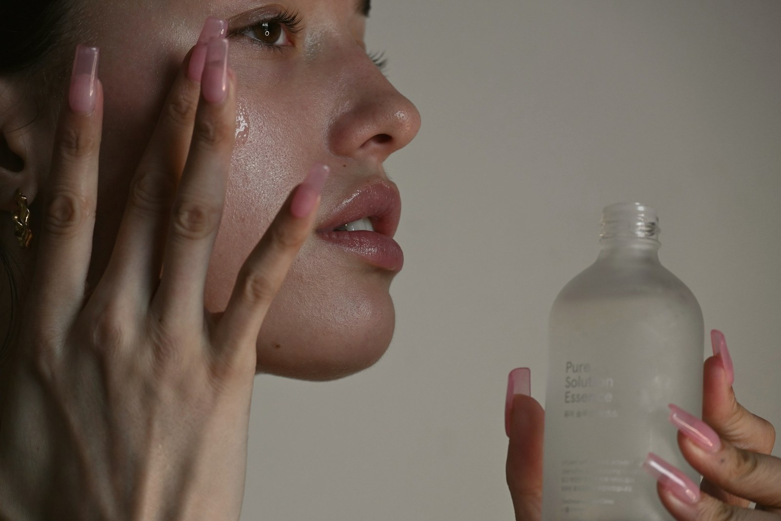 A woman applying serum to her cheek at close range