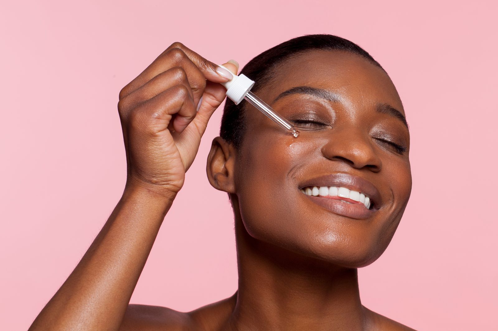 Woman applying a skincare serum with a dropper to her face